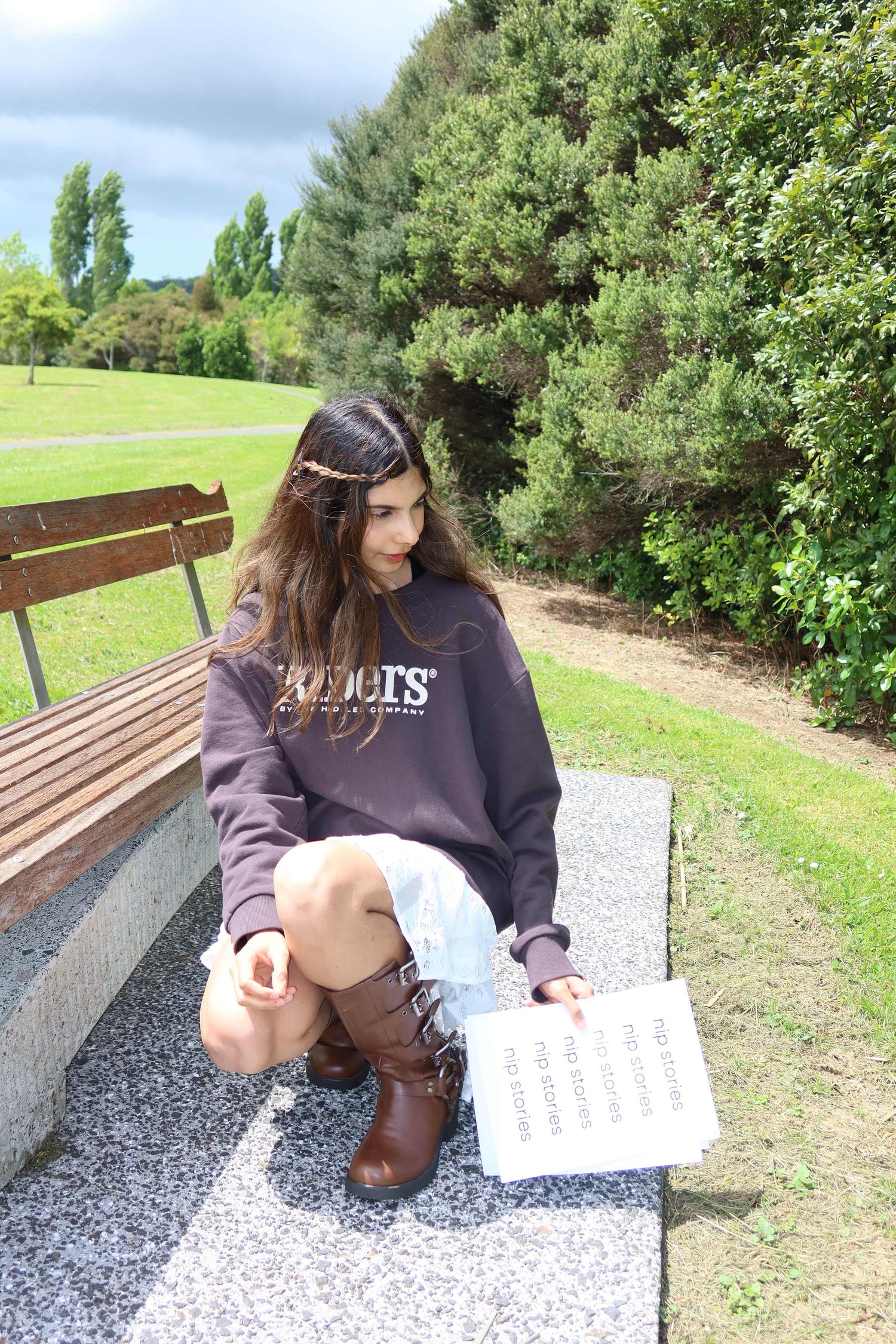 Woman holding Nip Stories card outdoors in NZ park