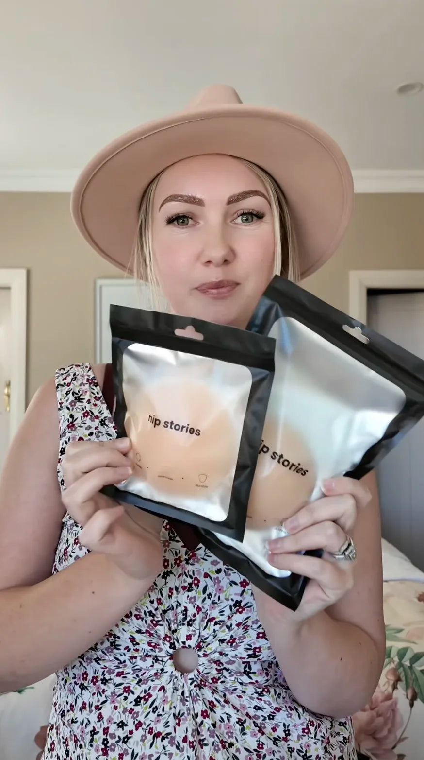 Woman holding two 'nip stories' product packages in a room.